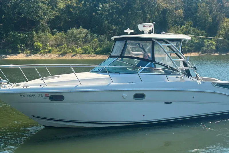 Slide: The Image of 2008 Sea Ray 290 Amberjack boat on calm water, surrounded by lush greenery. - 16