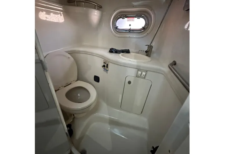 Slide: The Image of 2008 Sea Ray 290 Amberjack boat bathroom with toilet, sink, and porthole window. - 25