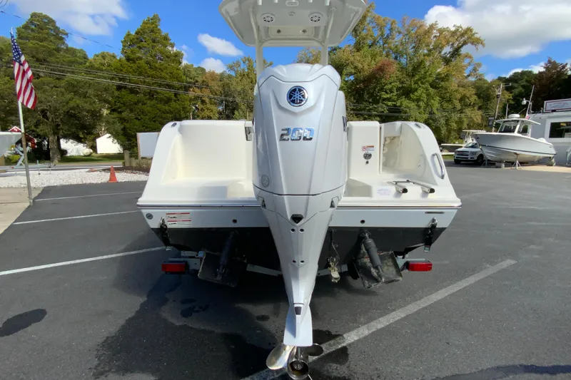 Slide: The Image of 2025 Cobia 220 Center Console boat with powerful outboard motor in a parking lot. - 10