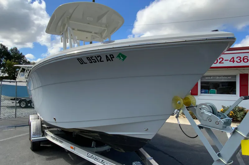 Slide: The Image of 2025 Cobia 220 Center Console boat on trailer, parked outdoors under cloudy sky. - 3