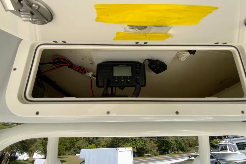 Slide: The Image of 2025 Cobia 220 Center Console boat's electronic compartment with Garmin device and wiring. - 36