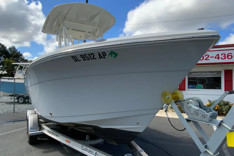 Slide: The Image of 2025 Cobia 220 Center Console boat on trailer, parked outdoors under a cloudy sky. - 4