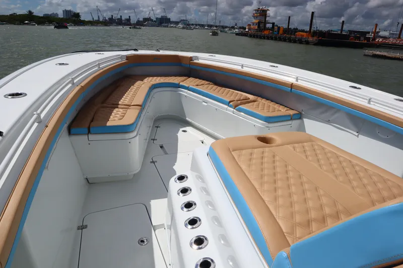 Slide: The Image of 2022 Yellowfin 42 Offshore boat with tan and blue cushioned seating, docked in a harbor. - 15