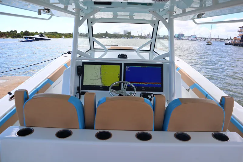 Slide: The Image of 2022 Yellowfin 42 Offshore boat cockpit with navigation screens and steering wheel, docked by the water. - 33