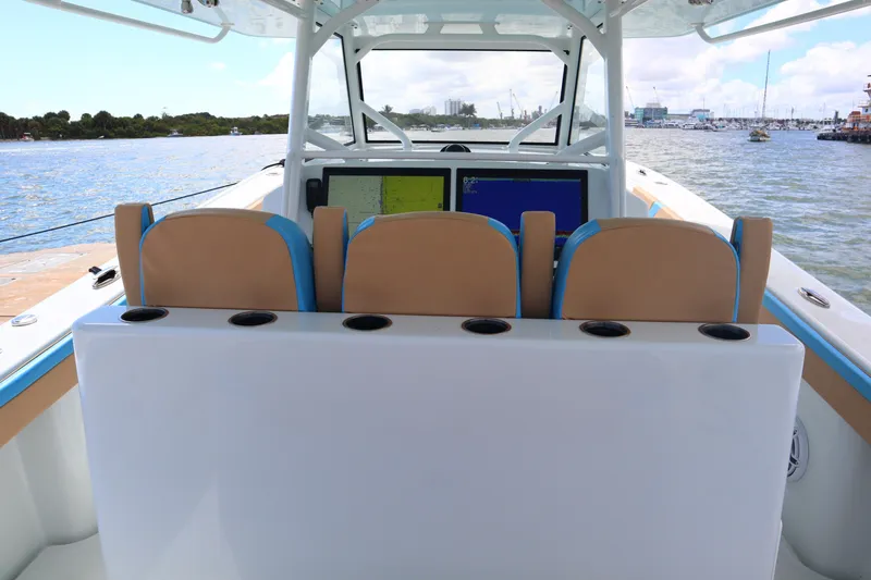 Slide: The Image of 2022 Yellowfin 42 Offshore boat interior with navigation screens and seating, on a calm waterway. - 36