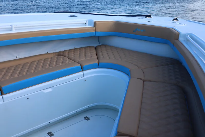 Slide: The Image of 2022 Yellowfin 42 Offshore boat interior with tan and blue cushioned seating. - 43