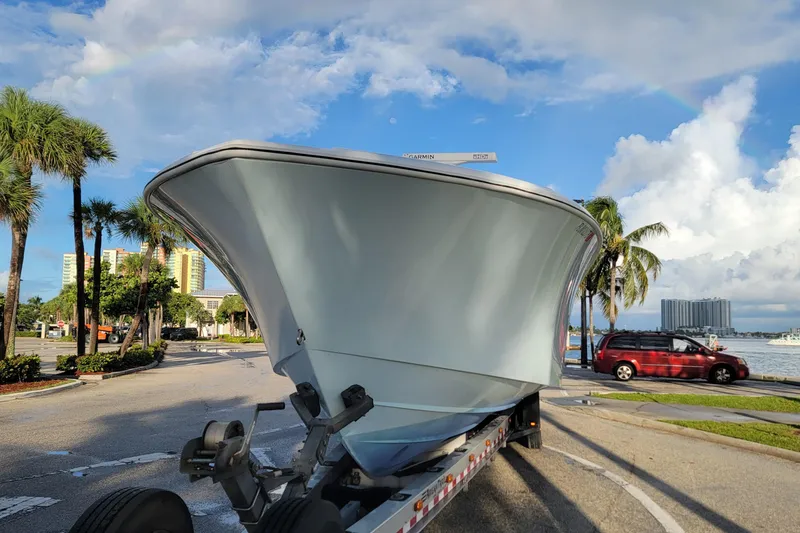 Slide: The Image of 2022 Yellowfin 42 Offshore boat on trailer, parked near waterfront with palm trees. - 6