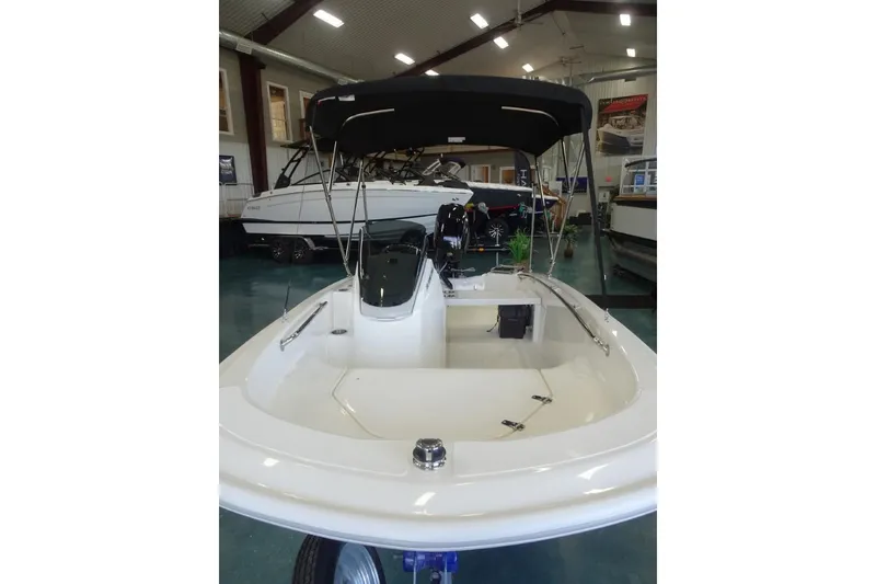 Slide: The Image of 2026 Boston Whaler 130 Super Sport boat displayed indoors with canopy. - 11