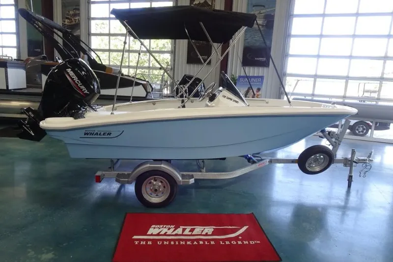 Slide: The Image of 2026 Boston Whaler 130 Super Sport boat on trailer in showroom. - 2