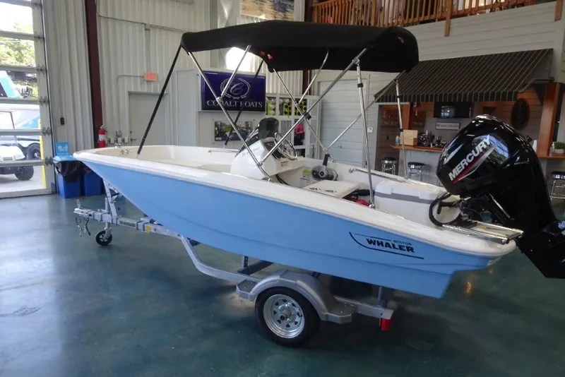 Slide: The Image of 2026 Boston Whaler 130 Super Sport boat with Mercury engine in showroom. - 7