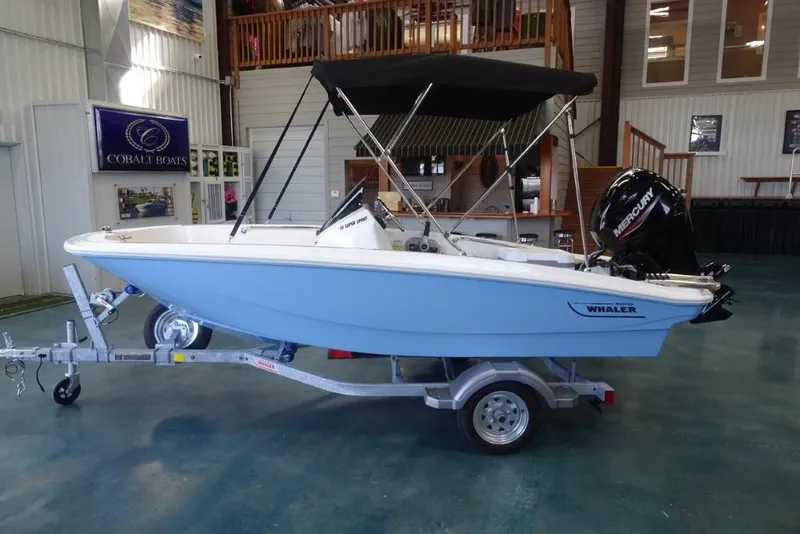 Slide: The Image of 2026 Boston Whaler 130 Super Sport boat on trailer in showroom. - 8