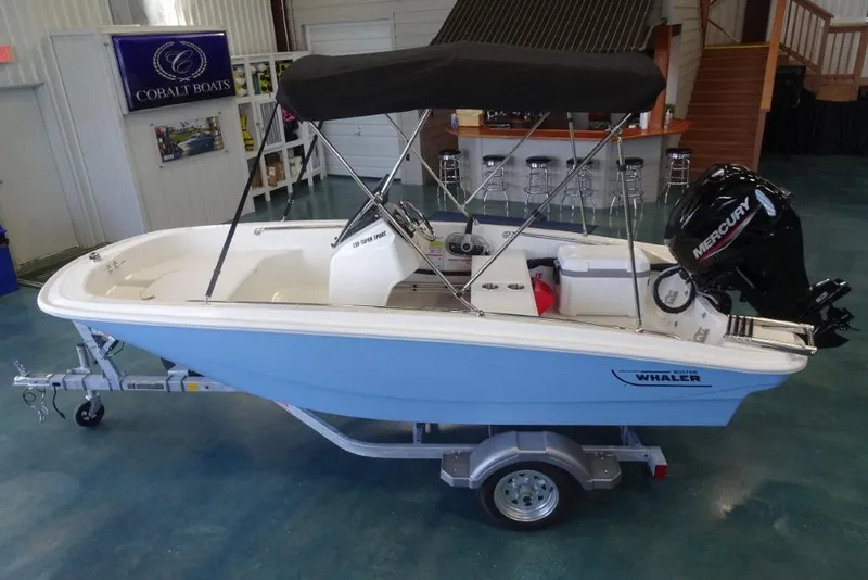 Slide: The Image of 2026 Boston Whaler 130 Super Sport boat with Mercury engine on trailer indoors. - 9