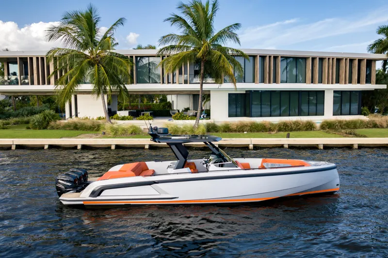 The Image of 2023 Vanquish Yachts Sports Line Outboard cruising by modern waterfront home. - 0