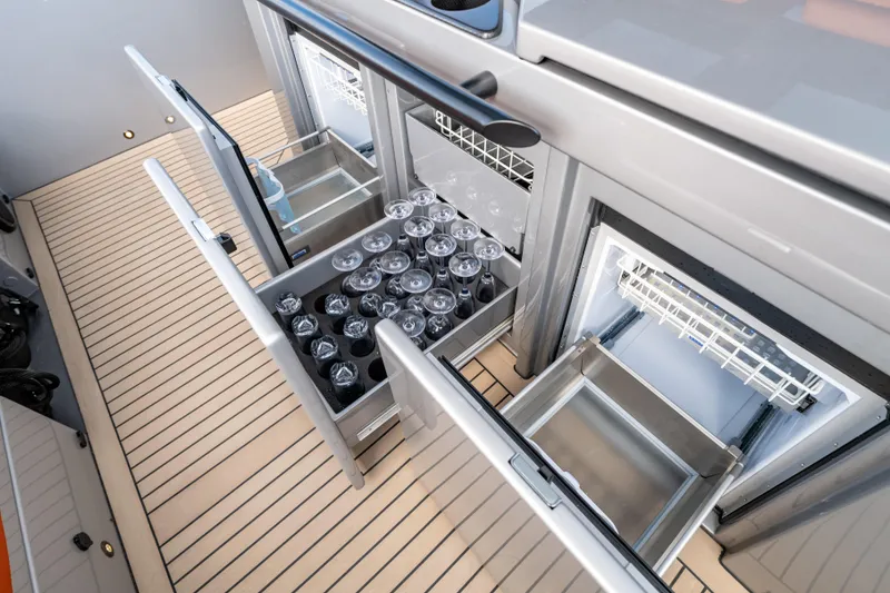 Slide: The Image of 2023 Vanquish Yachts Sports Line Outboard interior with open storage compartments and glassware. - 11