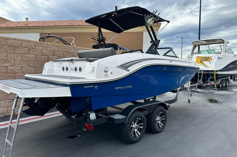 Slide: The Image of 2021 Bayliner DX 2050 boat on trailer, parked outdoors under a cloudy sky. - 2