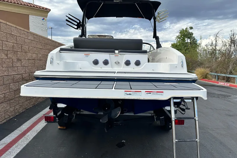 Slide: The Image of 2021 Bayliner DX 2050 boat on trailer, blue and white design, parked outdoors. - 4