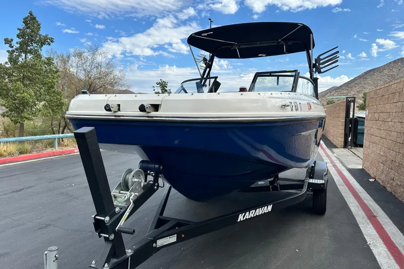 Slide: The Image of 2021 Bayliner DX 2050 boat interior with seating and steering wheel, docked outdoors. - 8