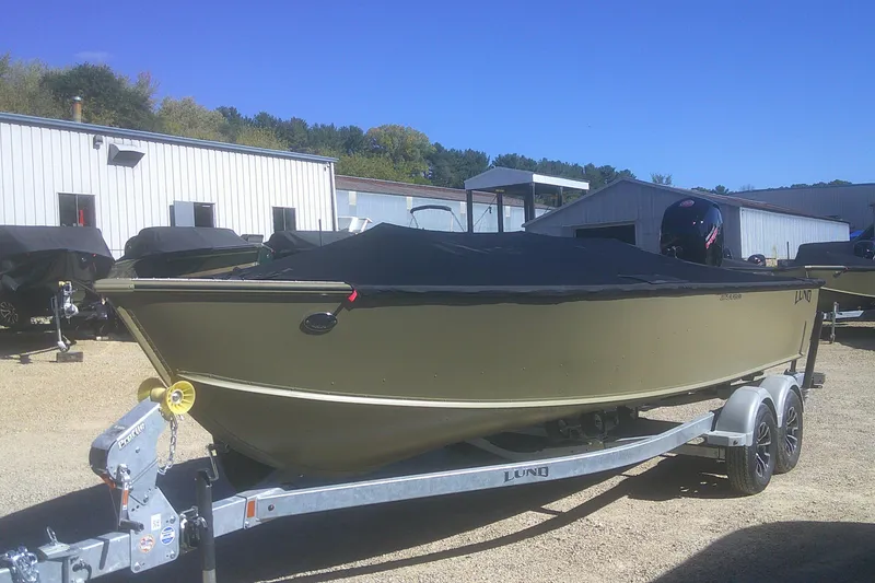 Slide: The Image of 2026 Lund 2075 Alaskan Tiller boat on trailer, covered, outdoors near buildings. - 14