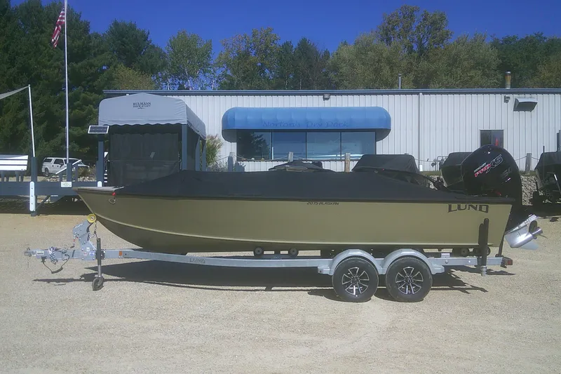 Slide: The Image of 2026 Lund 2075 Alaskan Tiller boat on trailer, parked outdoors near dealership. - 15