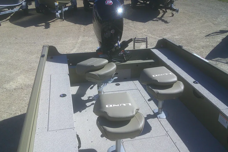 Slide: The Image of 2026 Lund 2075 Alaskan Tiller boat interior with seating and motor, parked on gravel. - 4