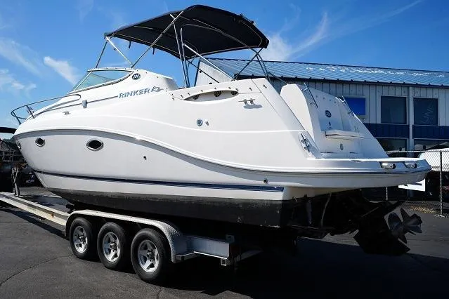 Slide: The Image of 2007 Rinker 280 Fiesta Vee boat on a trailer, parked outdoors under a clear blue sky. - 6