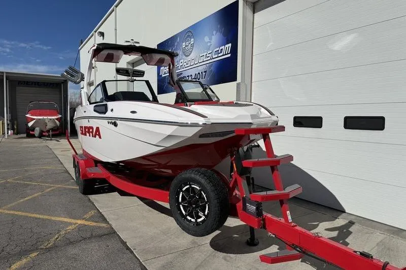 Slide: The Image of 2024 Supra SL 575 boat on red trailer outside dealership. - 3