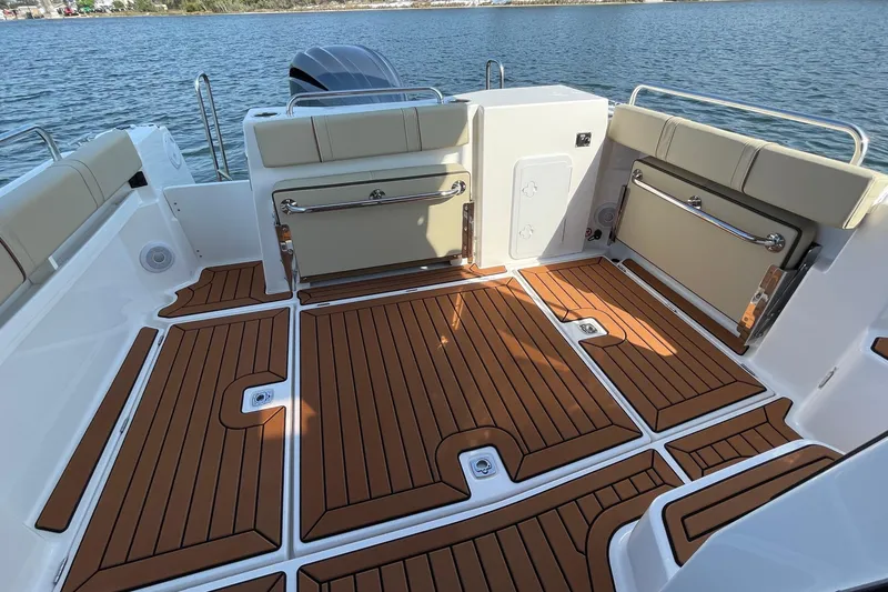 Slide: The Image of 2023 Ranger Tugs R-25 boat deck with teak flooring and cushioned seating. - 18