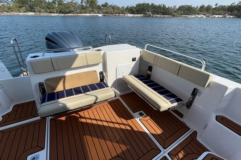 Slide: The Image of 2023 Ranger Tugs R-25 boat interior with cushioned seating and wooden deck. - 19