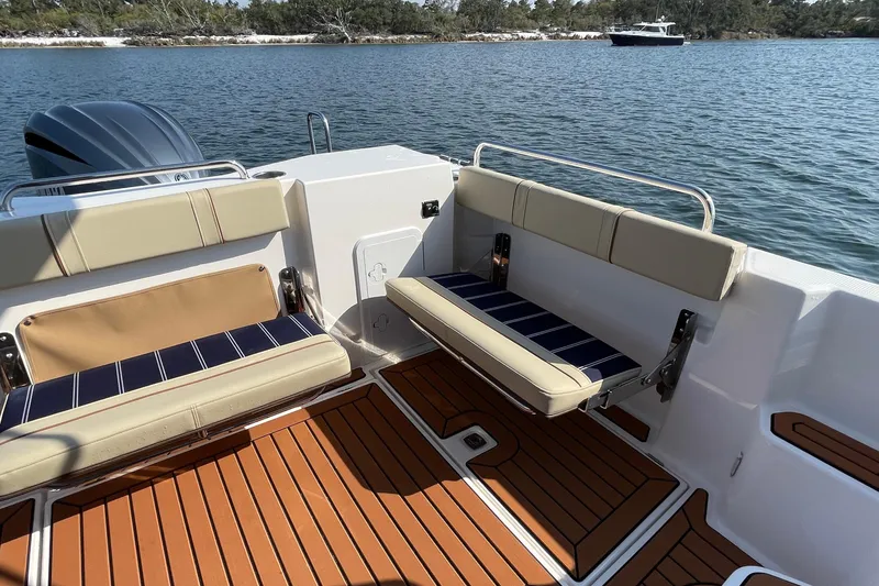 Slide: The Image of 2023 Ranger Tugs R-25 boat interior with cushioned seating and wood-style flooring on a calm lake. - 20