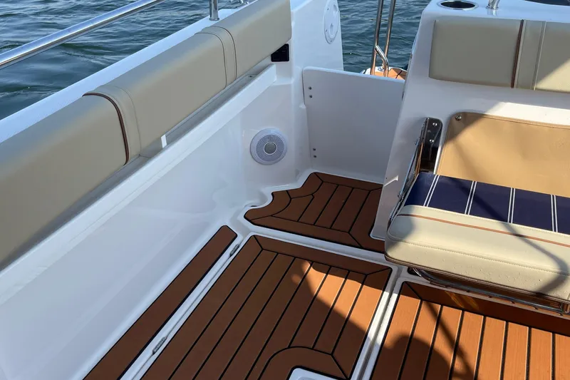 Slide: The Image of 2023 Ranger Tugs R-25 boat interior with cushioned seating and teak flooring. - 21