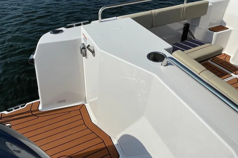 Slide: The Image of 2023 Ranger Tugs R-25 boat deck with seating and wood finish, near water. - 23