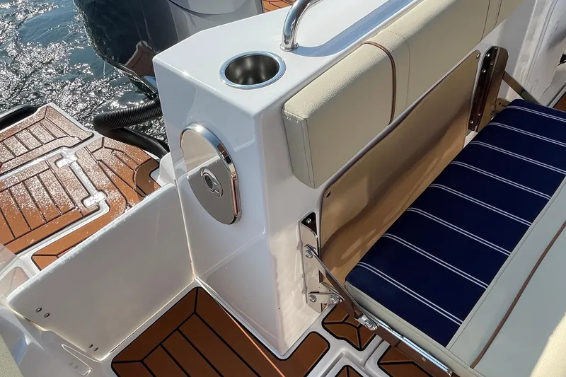 Slide: The Image of 2023 Ranger Tugs R-25 boat seating area with cup holder and striped cushion. - 24