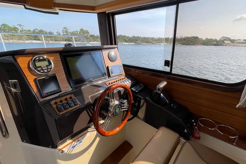 Slide: The Image of 2023 Ranger Tugs R-25 helm with wooden steering wheel and modern navigation equipment. - 29