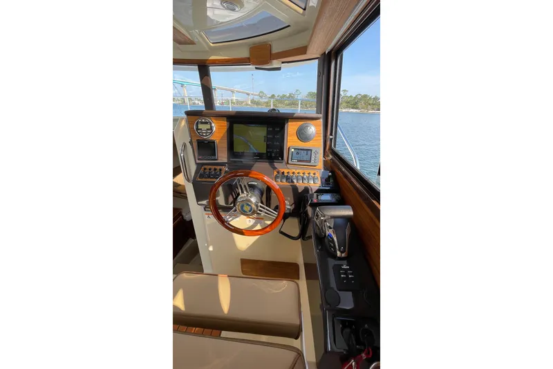 Slide: The Image of 2023 Ranger Tugs R-25 helm with wooden steering wheel and navigation controls. - 30