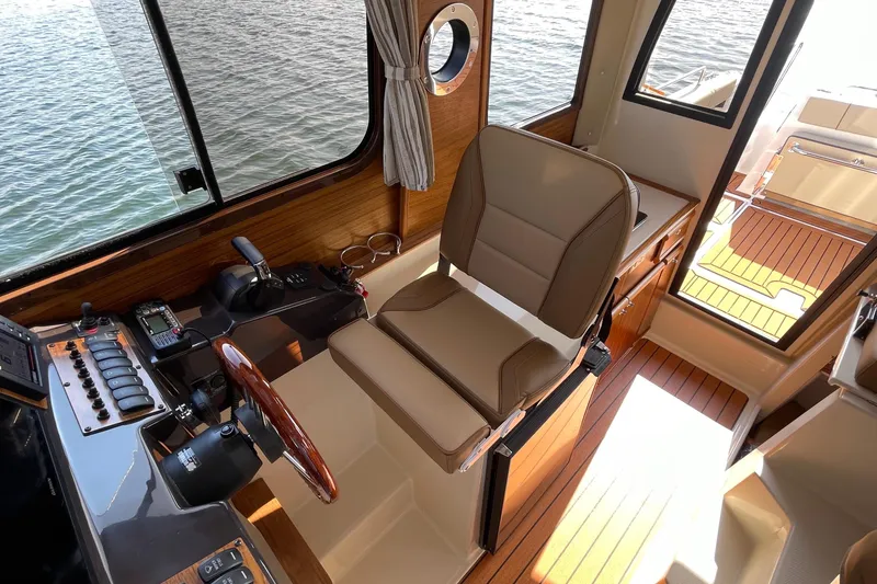 Slide: The Image of 2023 Ranger Tugs R-25 helm with luxurious seating and modern controls, overlooking water. - 34