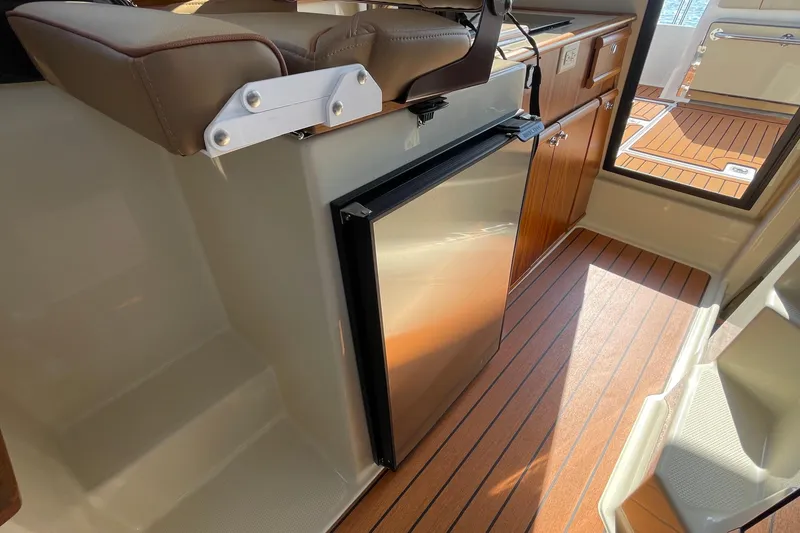 Slide: The Image of 2023 Ranger Tugs R-25 interior with wood flooring and compact refrigerator. - 35