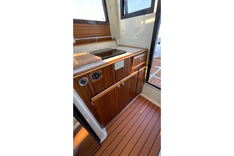Slide: The Image of 2023 Ranger Tugs R-25 interior with wooden cabinetry and compact kitchen area. - 37