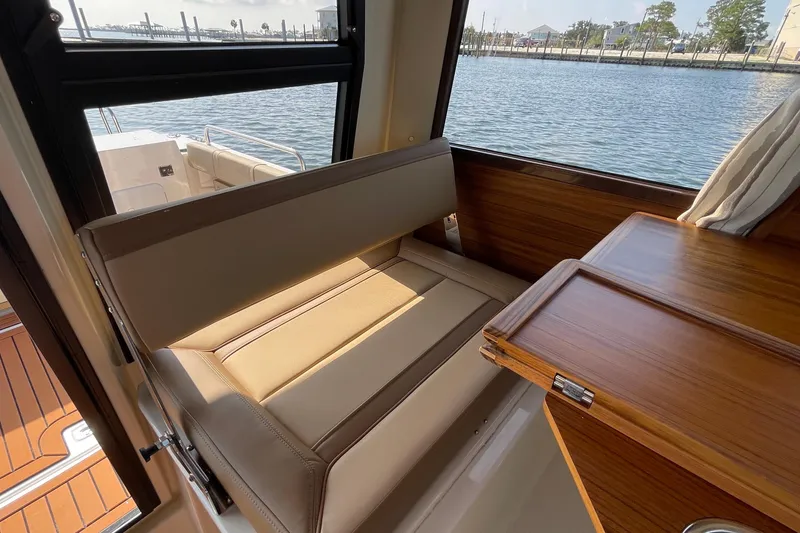 Slide: The Image of Interior of 2023 Ranger Tugs R-25 boat with beige seating and wooden table by the water. - 43