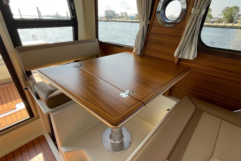 Slide: The Image of Interior of 2023 Ranger Tugs R-25, featuring a wooden dining table and seating by a window. - 44