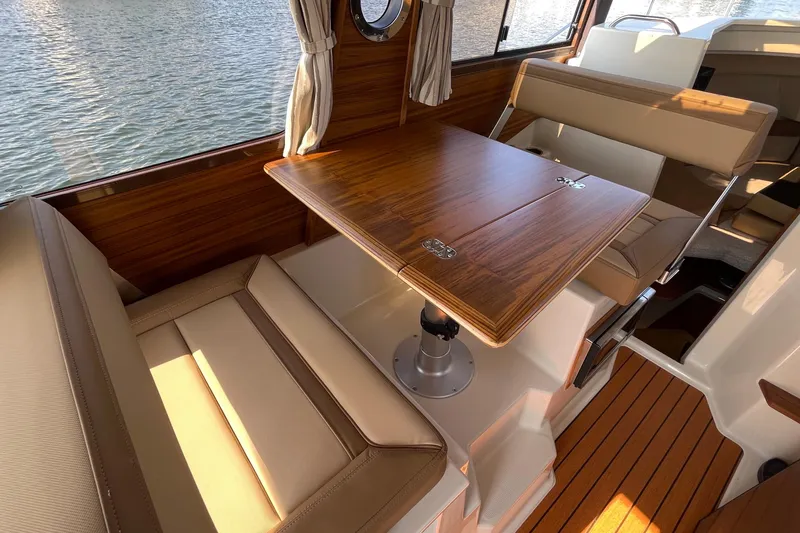 Slide: The Image of Interior of 2023 Ranger Tugs R-25, featuring a wooden table and cushioned seating. - 46