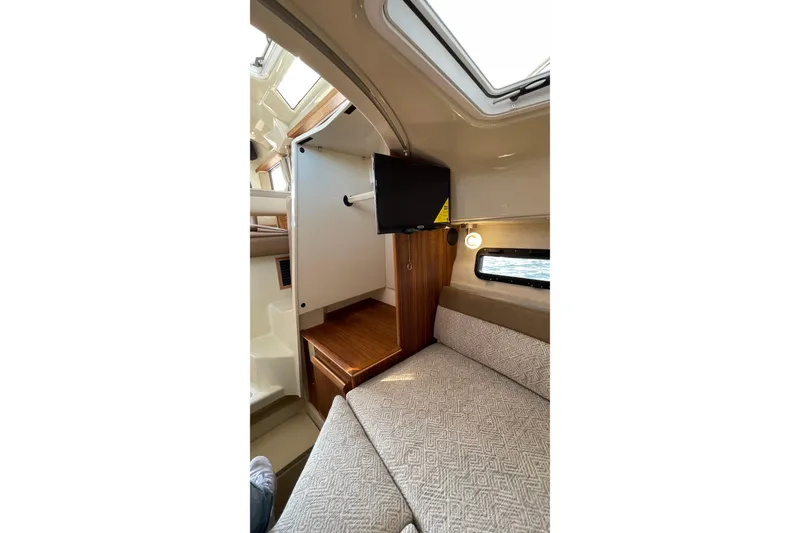 Slide: The Image of 2023 Ranger Tugs R-25 cabin interior with bed, TV, and window. - 48