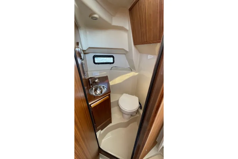 Slide: The Image of 2023 Ranger Tugs R-25 boat bathroom with sink, toilet, and wooden cabinetry. - 50