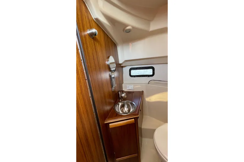Slide: The Image of 2023 Ranger Tugs R-25 interior bathroom with wooden cabinetry and stainless steel sink. - 51