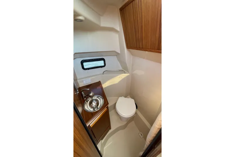 Slide: The Image of 2023 Ranger Tugs R-25 boat bathroom with sink, toilet, and wooden cabinetry. - 52