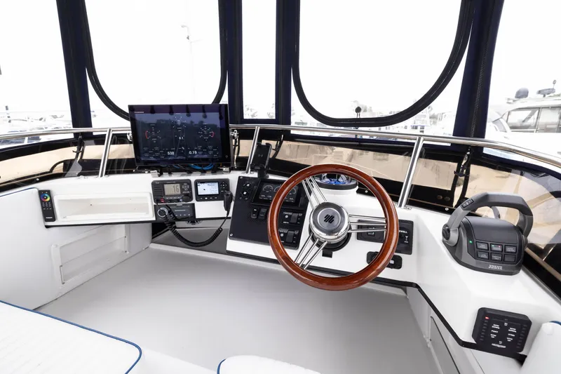 Slide: The Image of 2023 Skipjack 26 Flybridge helm with modern controls and wooden steering wheel. - 18