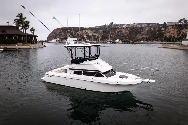 Slide: The Image of 2023 Skipjack 26 Flybridge boat in a scenic marina setting. - 2