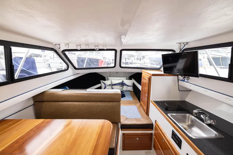 Slide: The Image of Interior of 2023 Skipjack 26 Flybridge boat with seating, kitchenette, and TV. - 26