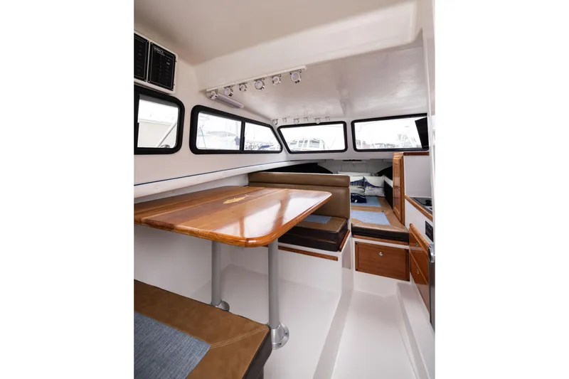 Slide: The Image of Interior of 2023 Skipjack 26 Flybridge boat with wooden table and seating area. - 27