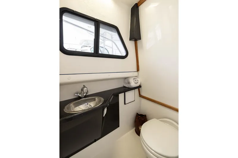 Slide: The Image of 2023 Skipjack 26 Flybridge boat bathroom with sink, window, and toilet. - 28