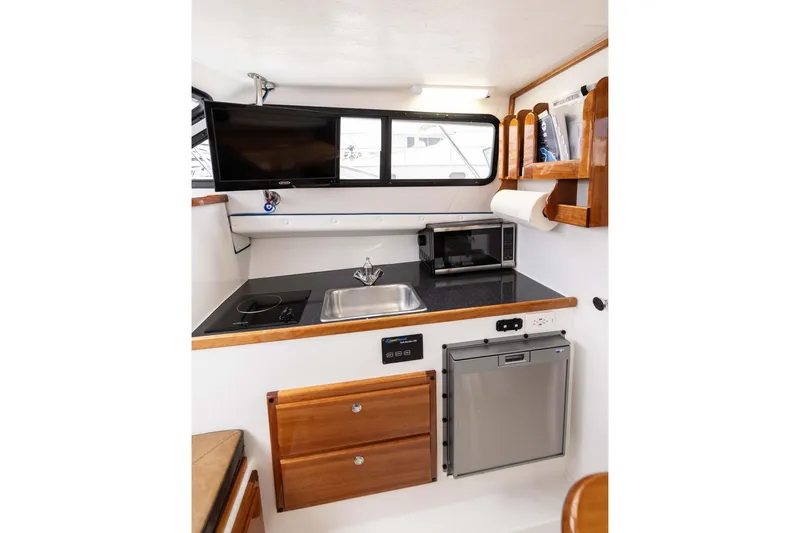 Slide: The Image of Modern galley in 2023 Skipjack 26 Flybridge boat with sink, stove, and microwave. - 29